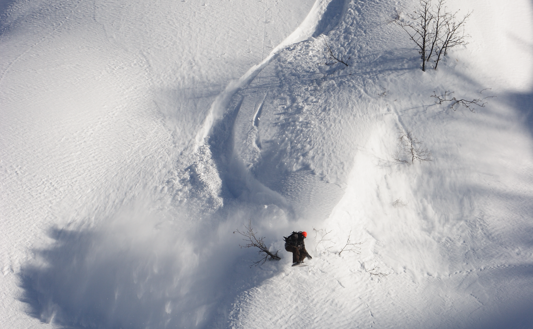 Russell snowboarding in Russia, carving a winding track through a broad snow-covered mountainside.